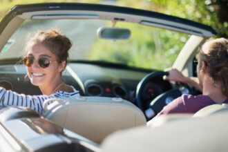 Couple profitant d'une balade en voiture décapotable en Bretagne