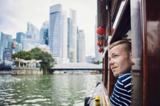Jeune homme admirant la ville depuis un bateau sur un fleuve